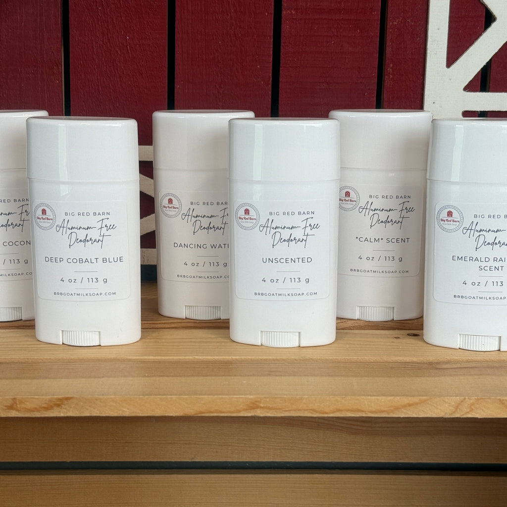 Row of white deodorant sticks on a wooden shelf with a red barn-like structure in the background.