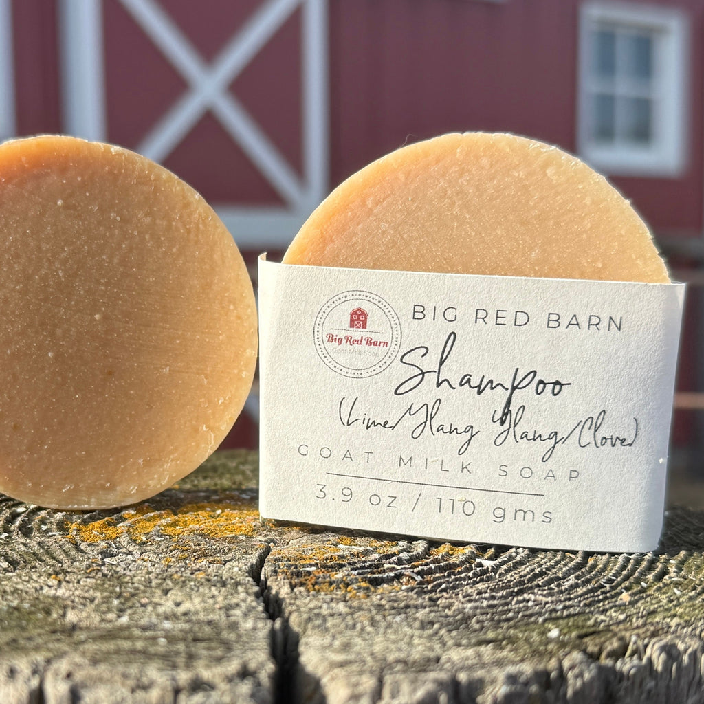 Bar of shampoo with a label on a wooden surface, red barn in the background