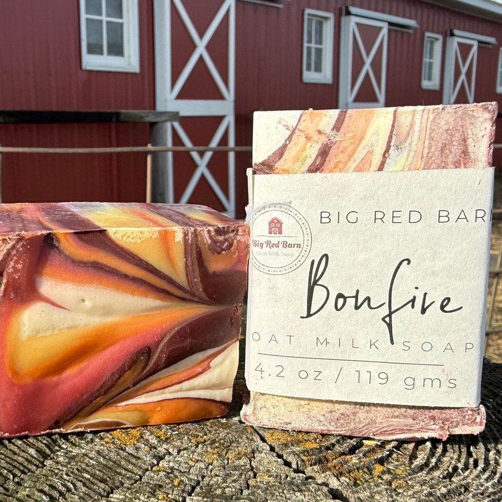 Two soap bars with packaging in front of a red barn.