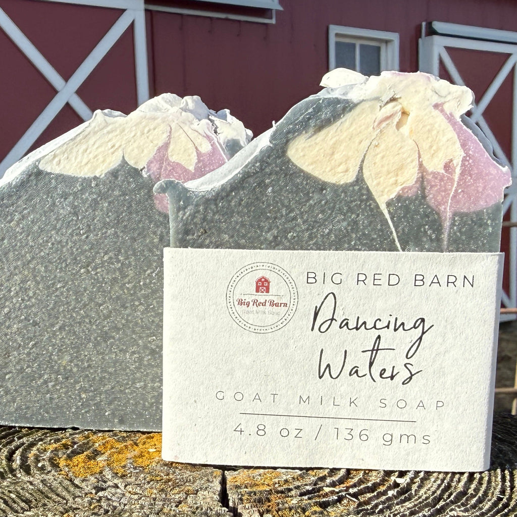 Goat milk soap bar with a label in front of a red barn.