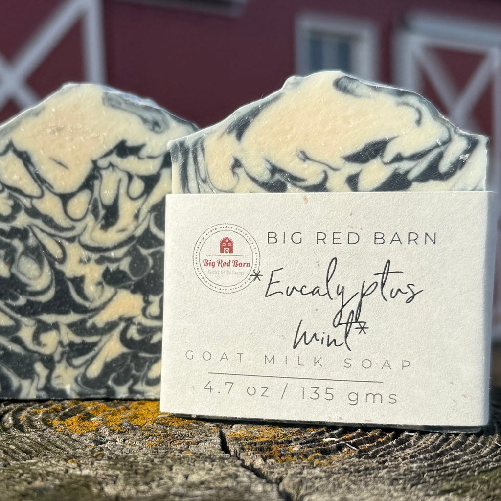Goat milk soap with a label in front of a red barn.