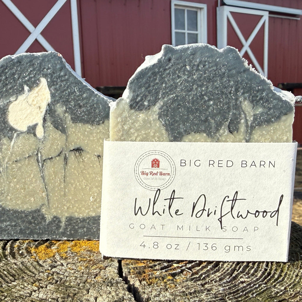 Two bars of soap on a log in front of a red barn.