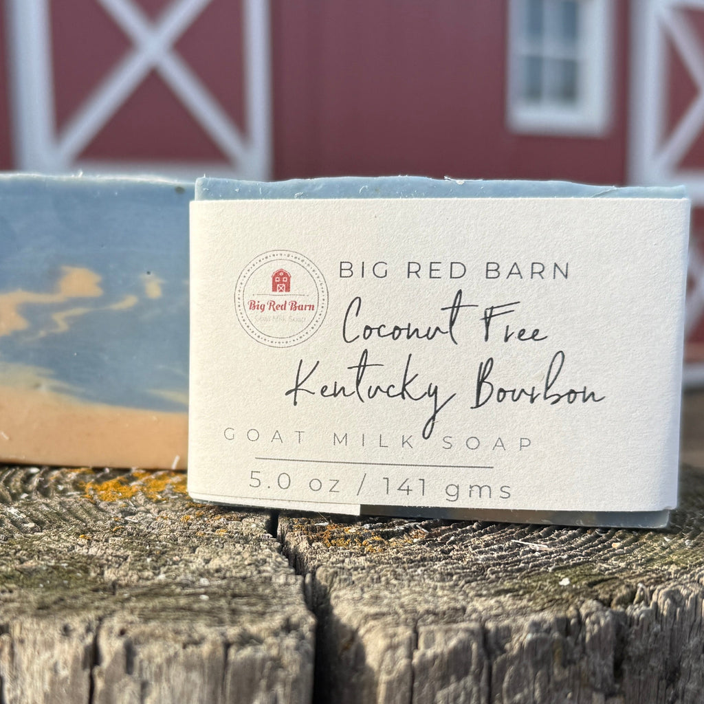 Bar of soap with packaging labeled 'Big Red Barn' on a wooden surface with a barn in the background.