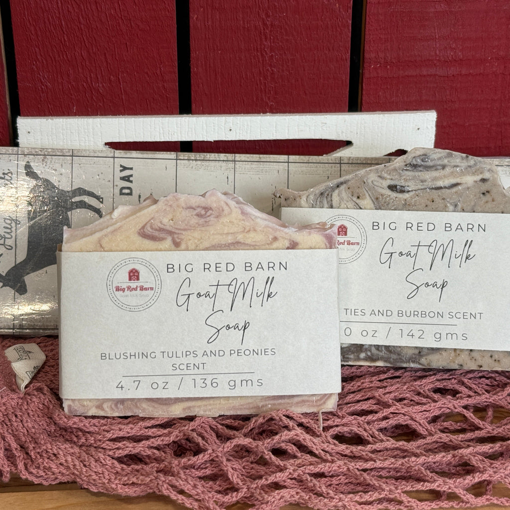 Two bars of soap with packaging on a pink textured surface and red wooden background